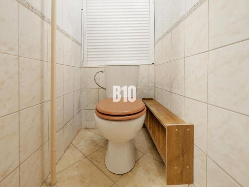 Fürdőszoba WC-vel és fa hatású padlóval egy kétszobás lakásban.