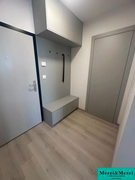Előszoba egy kétszobás lakásban fa dekoros padlóval és tárolóhellyel.
