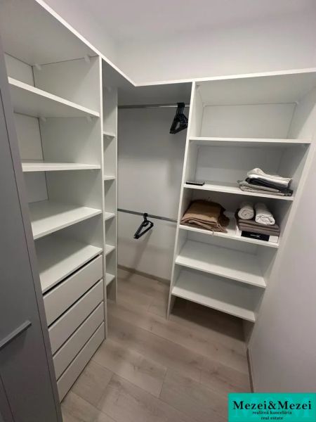 Tároló polcokkal, fiókokkal és fa dekorációjú padlóval egy kétszobás lakásban.