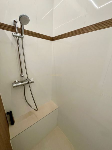 Zuhanykabin kézi zuhannyal és csempével egy háromszobás lakásban.