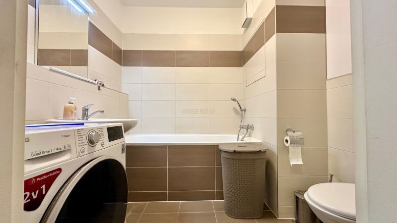 Fürdőszoba egy háromszobás lakásban káddal, mosógéppel és WC-vel.