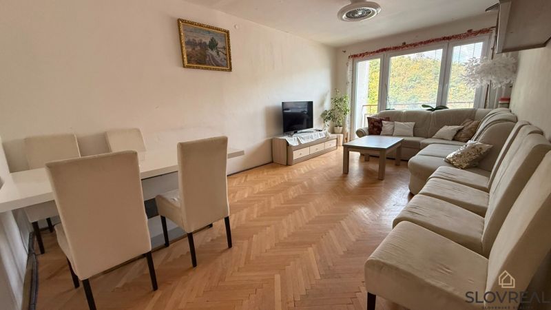 Nappali egy 4 szobás lakásban nagy kanapéval, étkezőasztallal és fa dekorációjú padlóval.