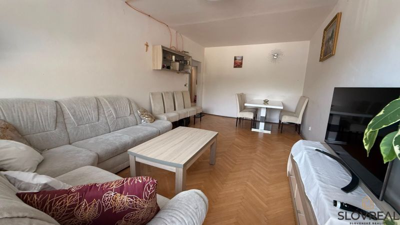 Nappali egy 4 szobás lakásban kényelmes ülőgarnitúrával és fa dekorációjú padlóval.