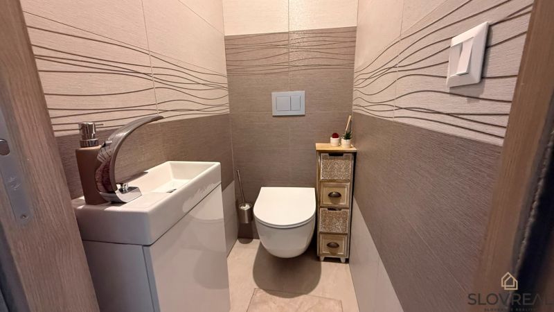 Hangulatos WC egyszerű mosdóval és dekoratív csempékkel egy 4 szobás lakásban.