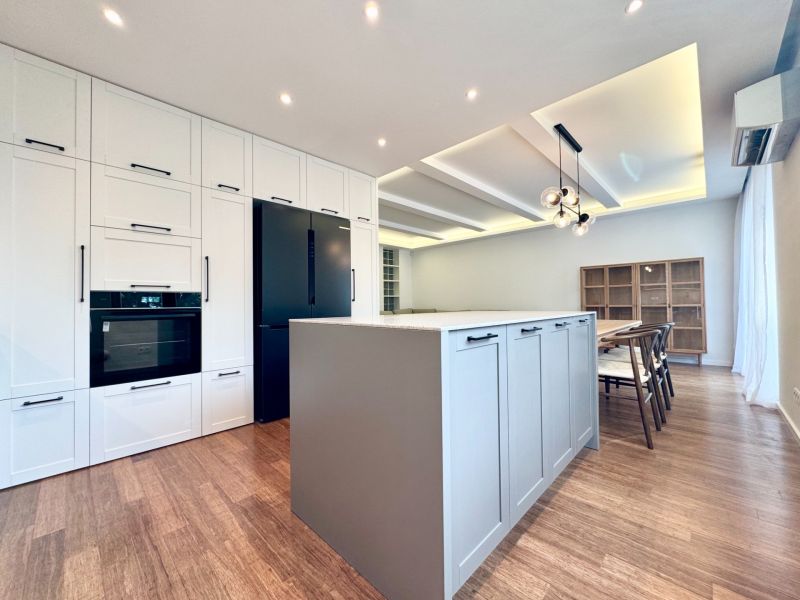 Konyha szigettel egy háromszobás lakásban, fa dekor padló, étkező.