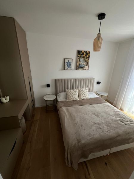 Hálószoba egy háromszobás lakásban ággyal, szekrénnyel és fa dekorú padlóval.