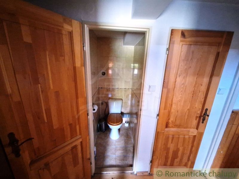 Kis fürdőszoba WC-vel, két ajtó, fa mintázatú padló.