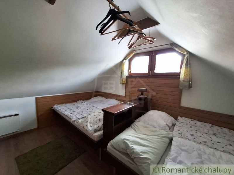 Padlás két ággyal, fa mintás padló, fogasok, kis ablak, alacsony mennyezet.