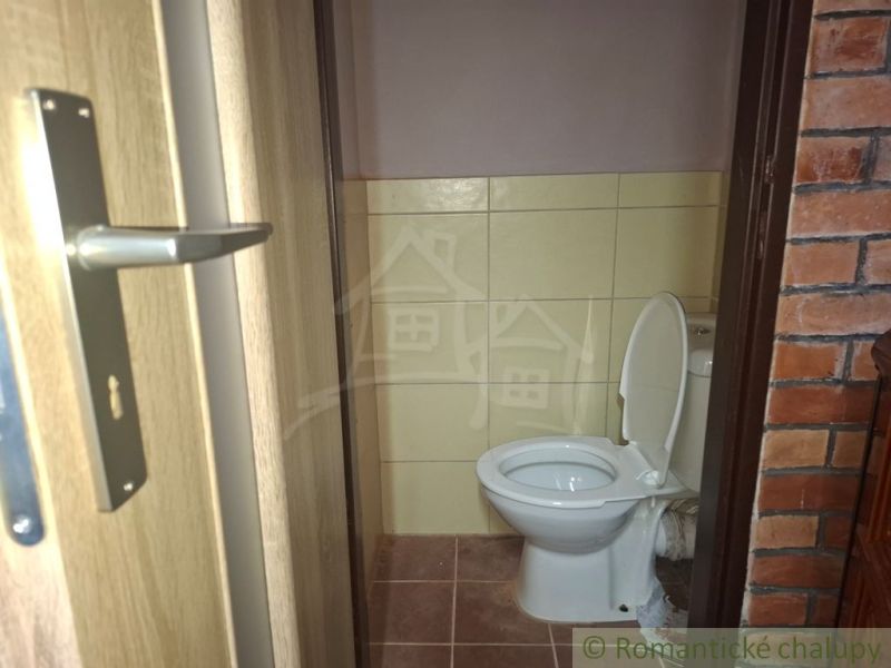 Toalett csempével és téglafallal a kunyhó belsejében.