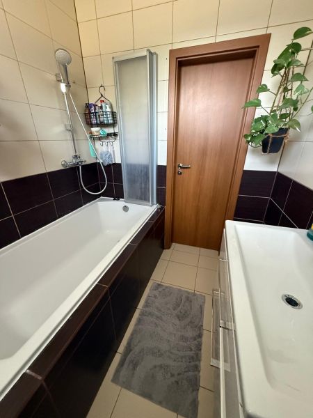 Fürdőszoba egy háromszobás lakásban káddal, mosdóval és csempével, amely kényelmet biztosít.