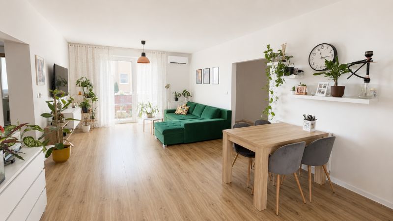 Nappali fa mintás padlóval, zöld kanapéval és növényekkel egy háromszobás lakásban.