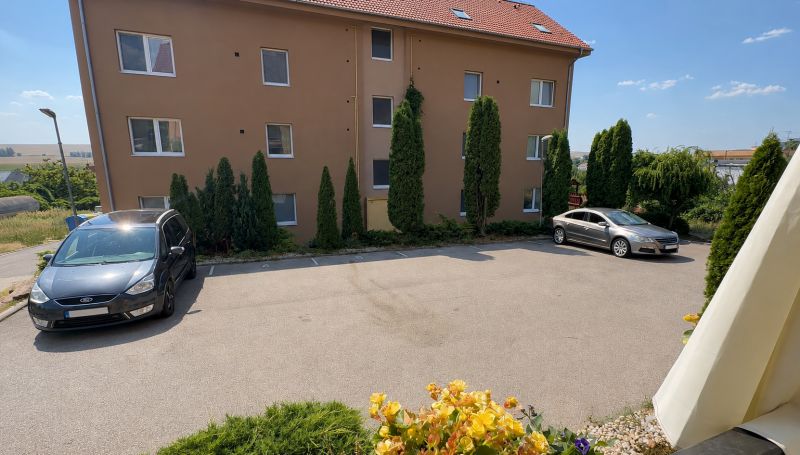Lakótelepi parkoló Nagylapáson autókkal és környező zöldterülettel.