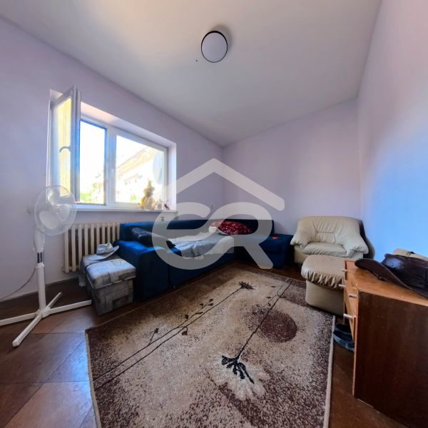 Nappali egy családi házban kék kanapéval, fotellel és szőnyeggel fa dekor padlón.