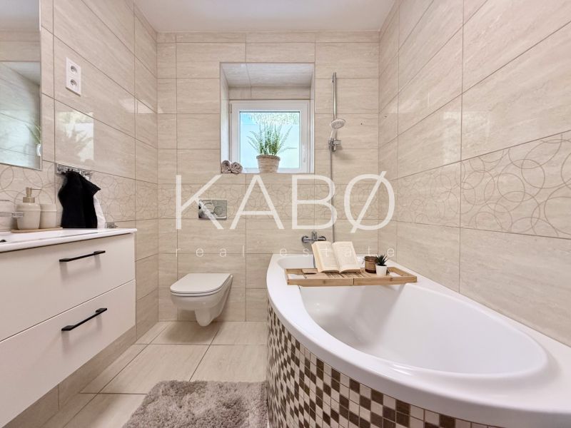 Elegáns fürdőszoba egy kétszobás lakásban káddal, mosdóval és WC-vel.