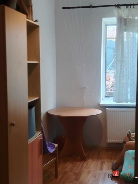 Egy szoba családi házban, fa dekorációjú padlóval, asztallal és polccal.