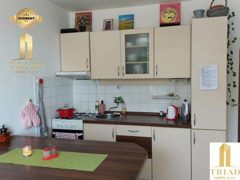 Konyha egy egyszobás lakásban, fa dekor padlóval és világos szekrényekkel.