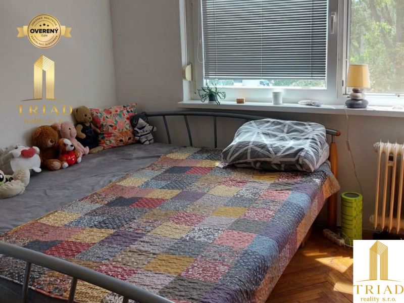 Hálószoba egy egyszobás lakásban, ággyal és egy halom plüssjátékkal az ágyon.