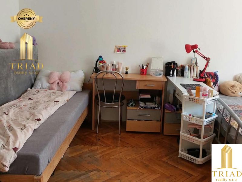 Diákszoba egy egyszobás lakásban, fa dekor padlóval és egyszerű bútorokkal.