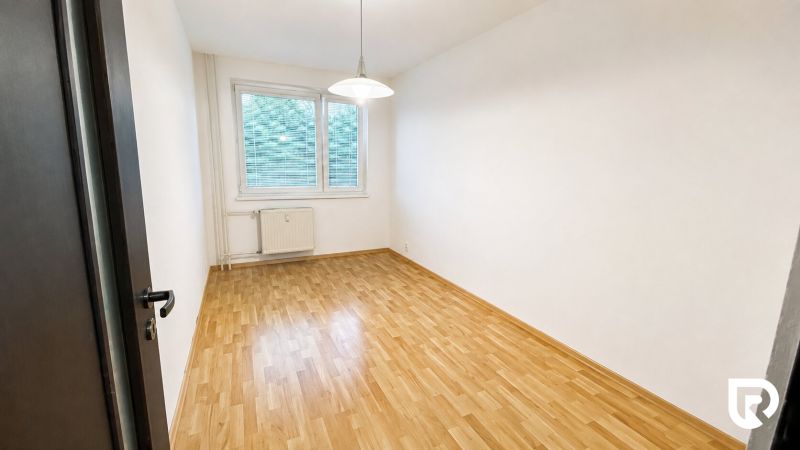 Üres szoba egy kétszobás lakásban, fa dekor padlóval és fehér falakkal.
