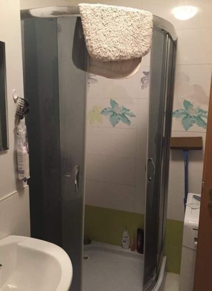 Két szobás lakás fürdőszobája zuhanyzóval és dekoratív csempével.