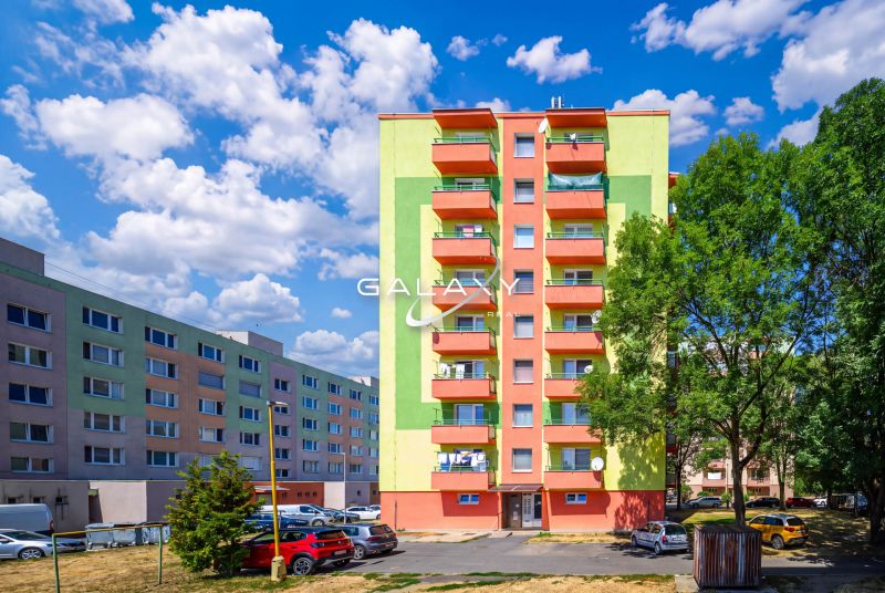 Színes lakóházak a Füleki Sládkovič utcában parkolóval és zöldterülettel.