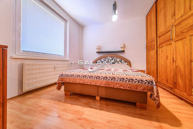 Hálószoba gardróbbal és fa dekor padlóval egy kétszobás lakásban.