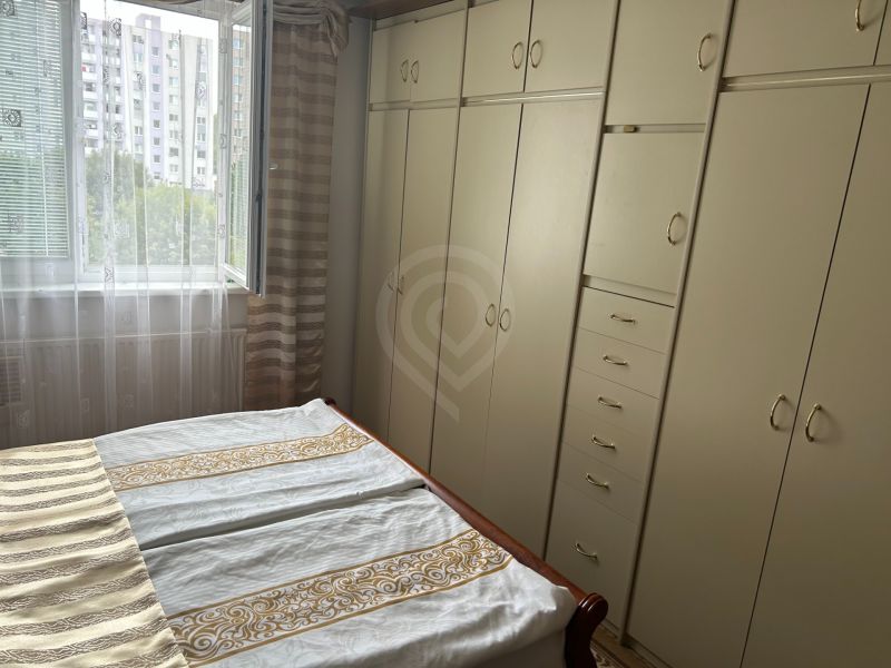 Hálószoba egy háromszobás lakásban beépített szekrényekkel és nyitott ablakkal a zöld környezetre.