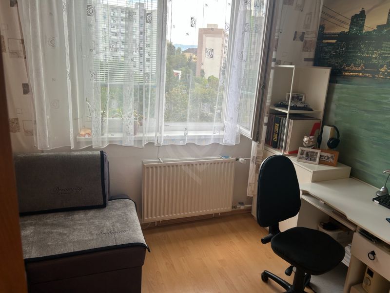Dolgozósarok egy háromszobás lakásban, fa dekor padlóval és íróasztallal.