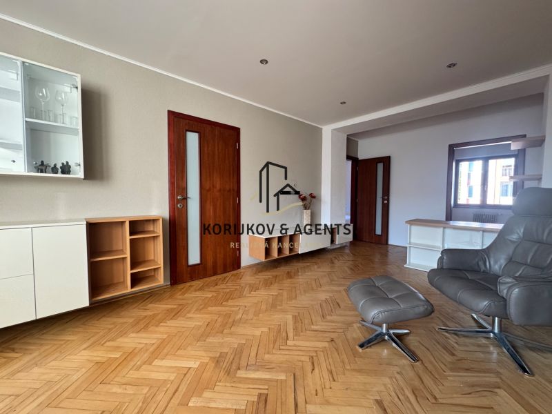 Nappali szoba kanapéval és fa dekor padlóval egy 4 szobás lakásban.