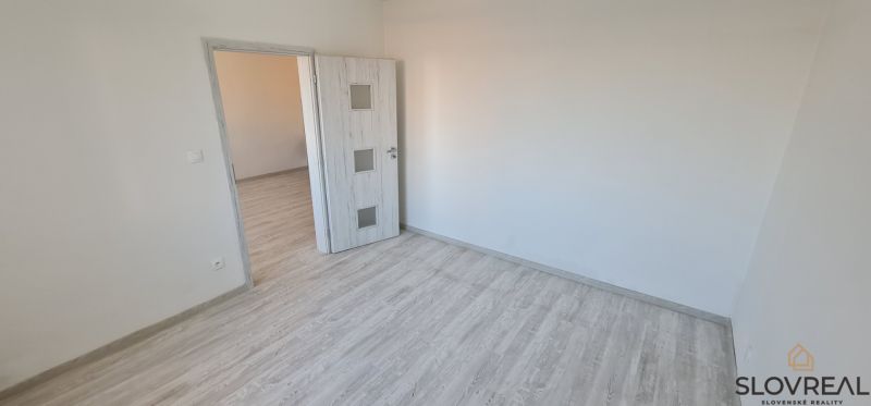 Szoba fa dekorációjú padlóval és fehér ajtókkal egy kétszobás lakásban.