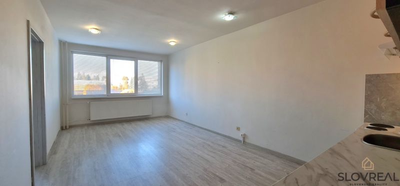 Világos szoba fa dekor padlóval egy kétszobás lakásban, nagy ablakkal.
