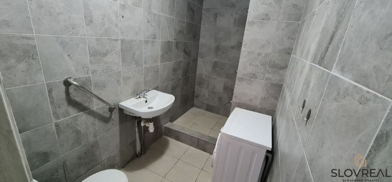 Fürdőszoba csempével, mosdó, WC és mosógép egy kétszobás lakásban.