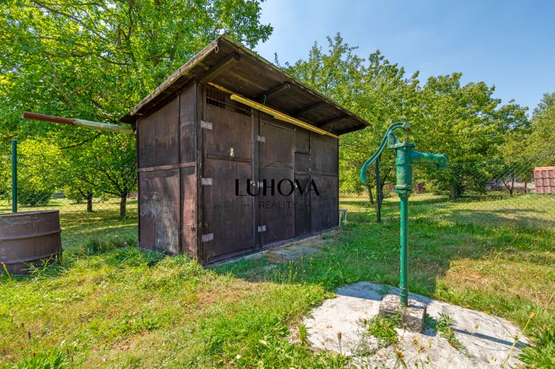 Fából készült pavilon és kézi szivattyú a kertben a Lazy pod Makytou, Dubková melletti háznál.