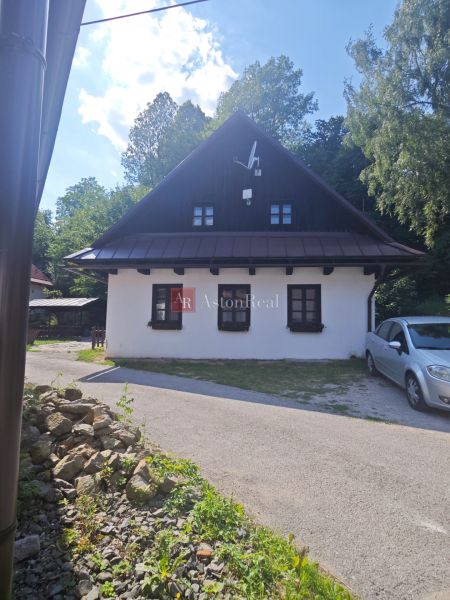 Ház Spania Dolinában fehér homlokzattal és műholdas antennával, zölddel körülvéve.