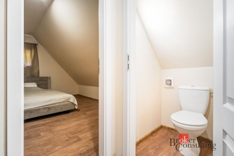 Hálószoba és WC fahatású padlóval rendelkező házikóban.