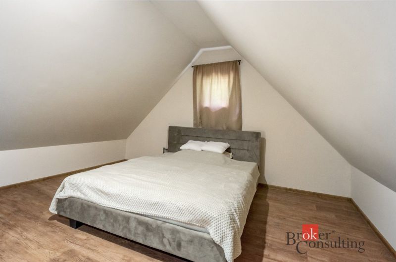 Tetőtéri hálószoba a házikóban, ággyal és fa dekorációjú padlóval.