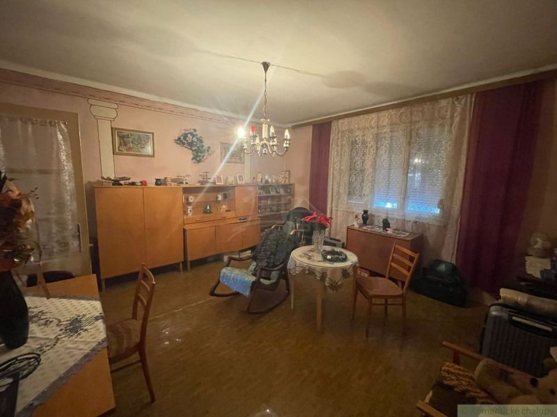 Nappali a családi házban bútorokkal, függönyökkel és fa mintázatú padlóval.