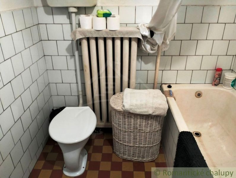 Fürdőszoba családi házban káddal, WC-vel, radiátorral és tároló kosárral.
