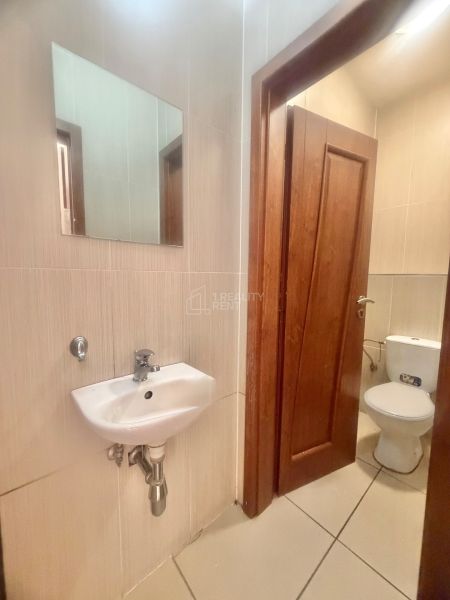 Kis fürdőszoba mosdóval, tükörrel és WC-vel üzlethelyiségben.
