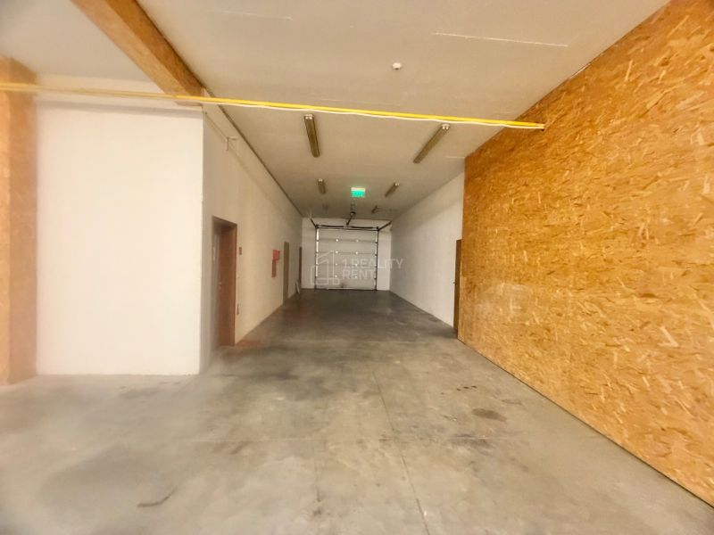 Tágas üzlethelyiségek betonpadlóval és fa falakkal.