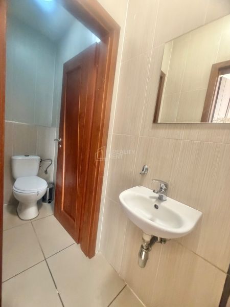 Kis fürdőszoba üzleti helyiségben WC-vel, mosdóval és tükörrel.