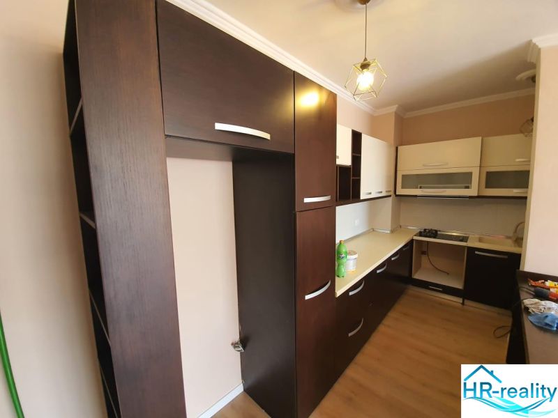 A Nyaraló apartman konyhája, ahol dominálnak a sötét szekrények és a fa dekorációjú padló.