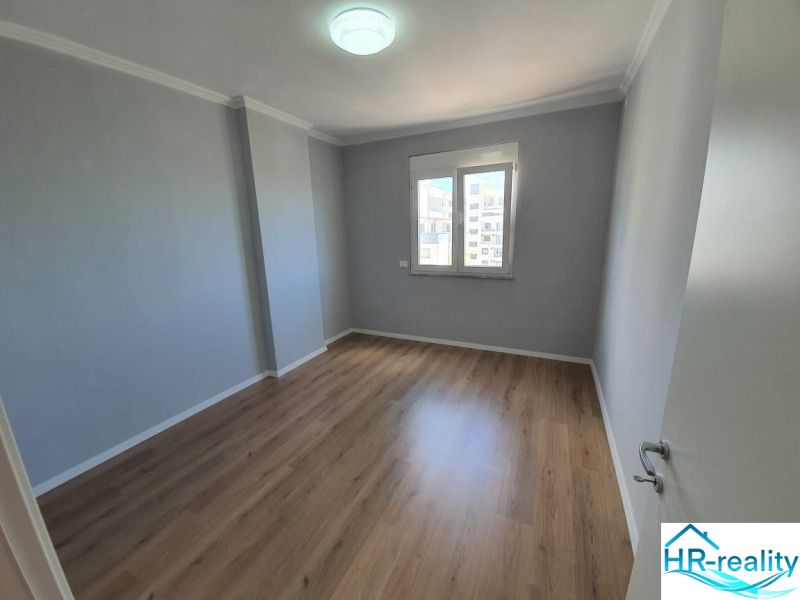 Szoba egy üdülő apartmanban fa dekor padlóval és ablakkal.