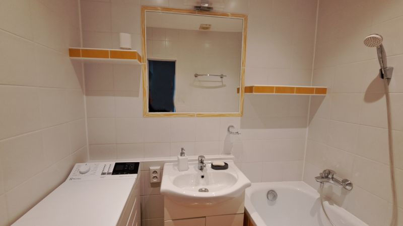 Fürdőszoba mosdóval, tükörrel, mosógéppel és káddal egy kétszobás lakásban.