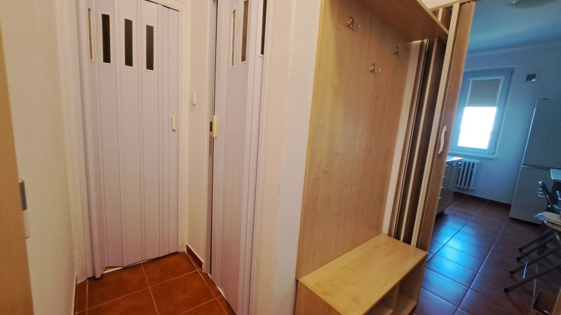 Barna csempével, gardróbszekrénnyel és tolóajtókkal ellátott bejárat egy kétszobás lakásban.