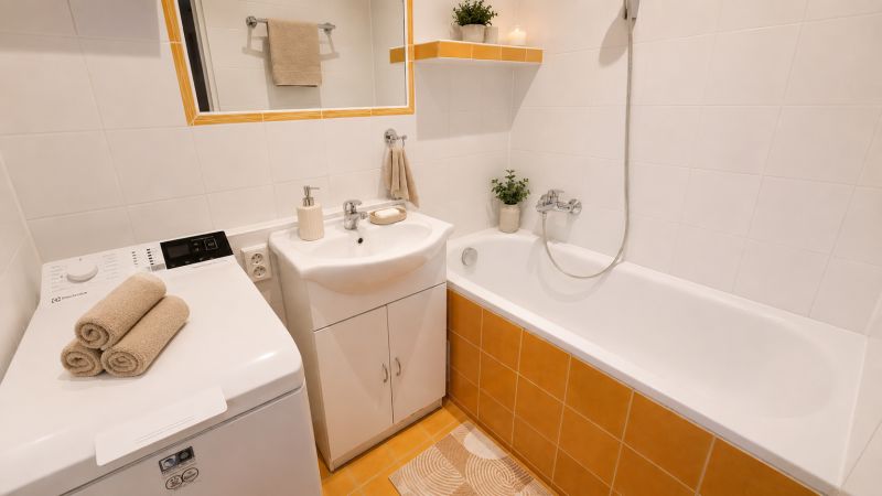 Fürdőszoba káddal, mosdóval, mosógéppel és dekoratív törölközőkkel egy kétszobás lakásban.