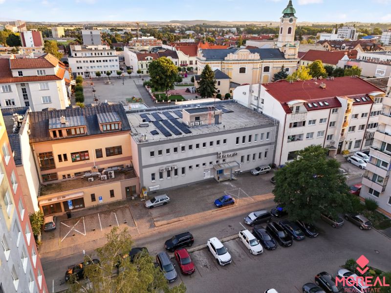 Kilátás M.R. Štefánikra Topoľčanyban üzlethelyiségekkel és templommal a háttérben.