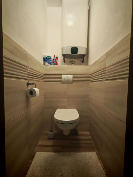 Fürdőszoba egy kétszobás lakásban WC-vel, falai és padlója fa hatású csempével burkolva.