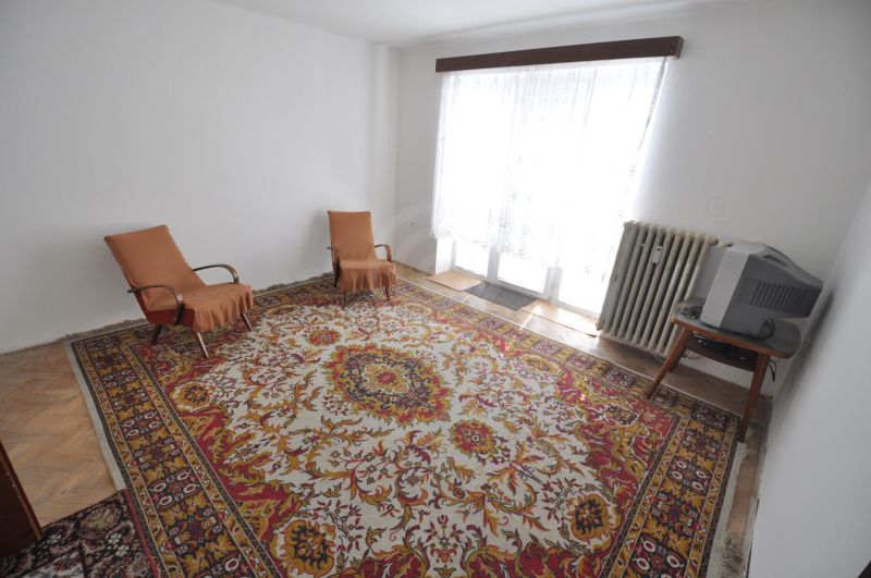 Nappali egy kétszobás lakásban szőnyeggel, két fotellel és televízióval.