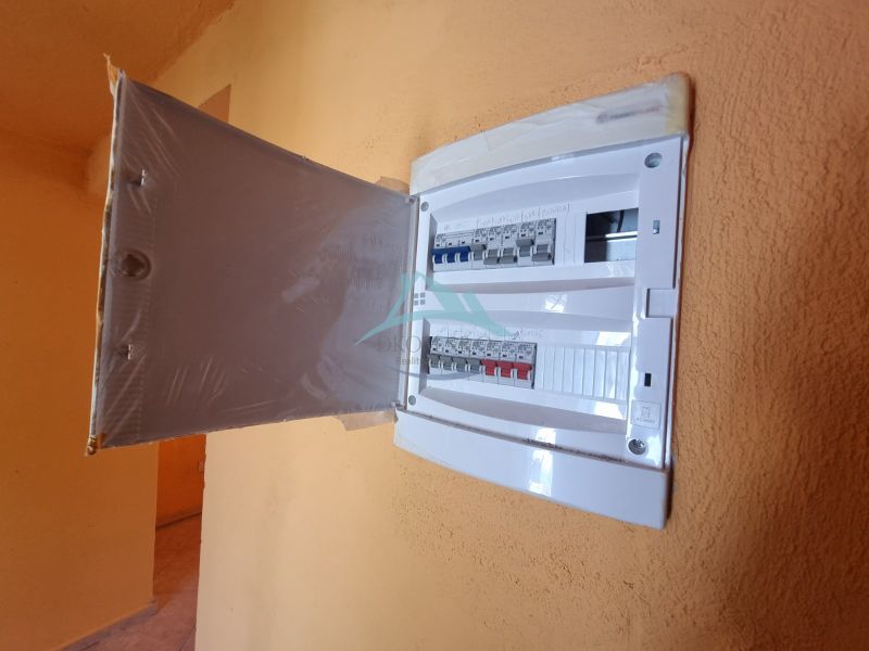 Elektromos elosztószekrény nyitott ajtókkal egy családi ház belső terében.